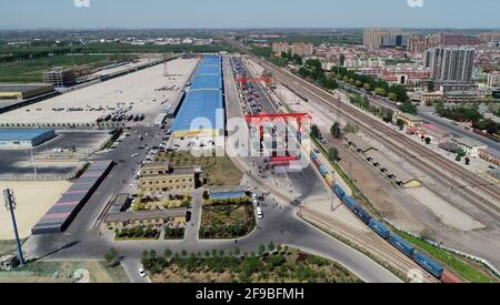 Shijiazhuang. April 2021. Das Luftfoto vom 17. April 2021 zeigt einen Güterzug nach Hamburg, Deutschland, der vom internationalen Landhafen Shijiazhuang in der nordchinesischen Provinz Hebei abfährt. Der erste China-Europa-Güterzug, der aus der Provinz Hebei nach Deutschland fuhr, fuhr am Samstag in Shijiazhuang. Der Zug, beladen mit 100 zwanzig Fuß Äquivalenteinheit (TEU) Ladung, wird voraussichtlich in 18 Tagen in Hamburg ankommen. Quelle: Zhang Xiaofeng/Xinhua/Alamy Live News Stockfoto