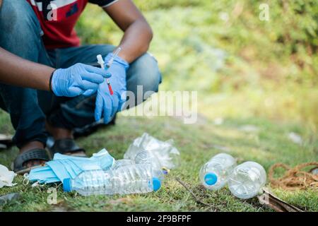 Nicht erkennbarer Freiwilliger oder Abfallsammler, der während des Coronavirus damit beschäftigt ist, weggeworfene medizinische oder PSA-Abfälle aus Plastikmüll zu trennen und zu sammeln Stockfoto