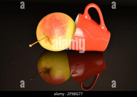 Ein frischer Bio-Apfel, saftig, süß, aromatisch, mit einer roten Keramikschale, Nahaufnahme, auf schwarzem Hintergrund. Stockfoto