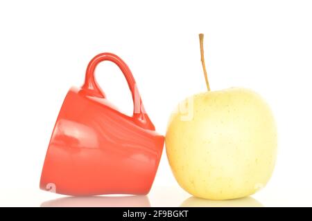 Ein reifer organischer, saftiger, duftender Apfel mit einer roten Keramikschale, Nahaufnahme, auf weißem Hintergrund. Stockfoto