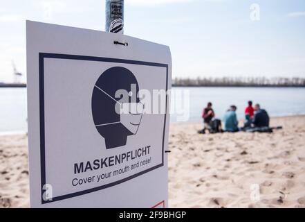 Hamburg, Deutschland. April 2021. Am Strand an der Elbe bei Övelgönne hängt ein Schild mit der Aufschrift „Maskenpflicht“ in der Sonne. Quelle: Daniel Bockwoldt/dpa/Daniel Bockwoldt/dpa/Alamy Live News Stockfoto