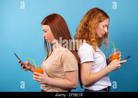 Ernsthafte junge Frauen lesen täglich, wichtige Nachrichten auf Smartphones trinken Cocktails. Studenten, Freunde mit moderner Technik und trinken gesund Stockfoto