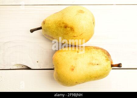 Zwei gelbe reife Birnen auf einem bemalten Holztisch. Stockfoto