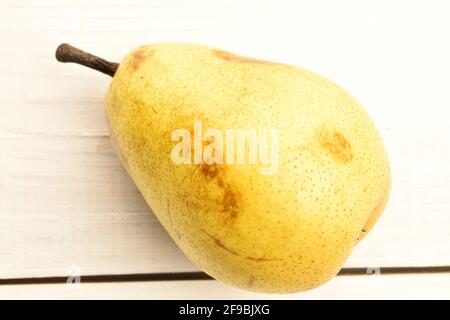 Eine gelbe reife Birne auf einem bemalten Holztisch. Stockfoto