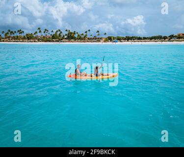 Paar Kajakfahren im Meer auf Urlaub Aruba Karibisches Meer, Mann und Frau mittleren Alters Kajak im Ozean blauen Clrea Wasser weißen Strand und Palmen Aruba Stockfoto