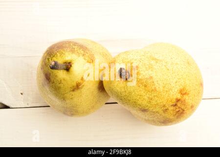 Zwei gelbe reife Birnen auf einem bemalten Holztisch. Stockfoto