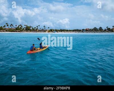 Paar Kajakfahren im Meer auf Urlaub Aruba Karibisches Meer, Mann und Frau mittleren Alters Kajak im Ozean blauen Clrea Wasser weißen Strand und Palmen Aruba Stockfoto