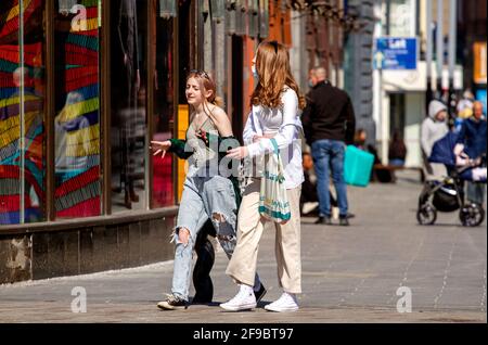 Dundee, Tayside, Schottland, Großbritannien. April 2021. UK Wetter: Schöner Frühlingssonne in Nordostschottland mit Temperaturen von bis zu 14 Grad Die Sperrung von Covid-19 wird gelockert, da die Menschen im Stadtzentrum von Dundee zusammenkommen und wichtige Einzelhandelsgeschäfte immer noch geöffnet sind. Zwei junge, modische Frauen nutzen die neuen, entspannten Sperrbestimmungen und das sonnige Aprilwetter, die nach einem Tag beim Shoppen gemeinsam Spaß haben. Kredit: Dundee Photographics/Alamy Live Nachrichten Stockfoto