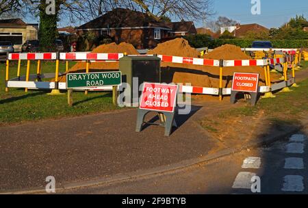 In einem Wohngebiet in Hellesdon, Norfolk, England, Großbritannien, wurden Erdhaufen gelagert, die bei Versorgungsgrabungen mit geschlossenen Hinweisschildern gelagert wurden. Stockfoto