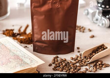Leere Kaffeeverpackung mit Kaffeesamen, Buch und Glas mit gemahlenem Kaffee, Kaffeeverpackung Mockup mit leerem Raum, um Ihr Branding des zu zeigen Stockfoto