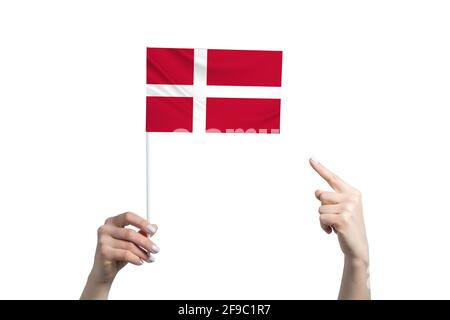 Eine schöne weibliche Hand hält eine dänische Flagge, auf der sie den Finger ihrer anderen Hand zeigt, isoliert auf weißem Hintergrund. Stockfoto