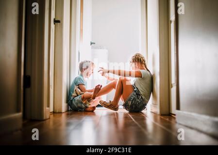 Bruder und Schwester spielen und lachen im hellen Flur Stockfoto