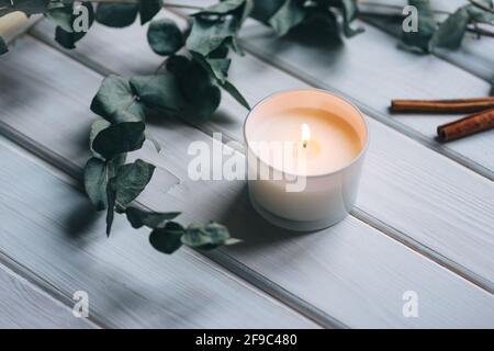 Kerze, Eukalyptus, Zimt auf weißem Holzhintergrund Stockfoto