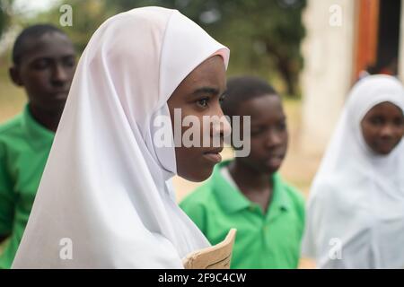 Dodoma, Tansania. 08-18-2019. Porträt einer attraktiven schwarzen jungen Frau, die sich mit einigen Schulkameraden trifft, um nach der Klassenarbeit zu diskutieren. Stockfoto