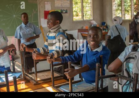 Dodoma, Tansania. 08-18-2019. Eine Gruppe lächelnder schwarzer Schüler packen ihre Sachen in ihrem Klassenzimmer, bevor sie nach einem Tag in der Schule nach Hause gehen. Stockfoto