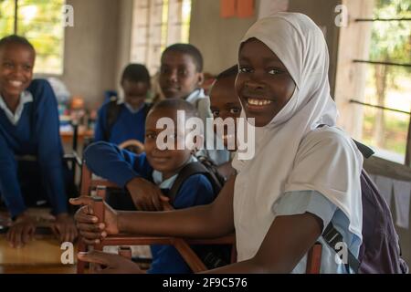 Dodoma, Tansania. 08-18-2019. Porträt einer Gruppe von Kindern in der Schule, die lächelnd auf die Kamera schauen, nachdem sie ihre Sachen verpackt und bereit sind, sie zu verlassen Stockfoto