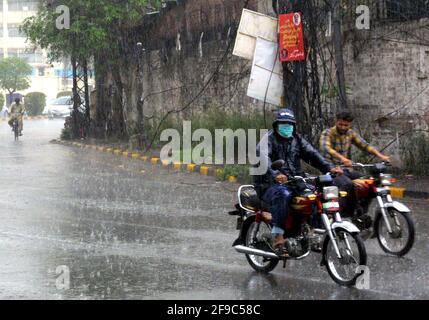 Pendler, die am Samstag, den 17. April 2021, bei starkem Regenguss in Lahore durch die Straße fahren. Stockfoto