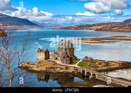 EILEAN DONAN CASTLE LOCH DUICH HIGHLANDS SCHOTTLAND BLAUER HIMMEL UND EIN BLAUES LOCH IM FRÜHLING BERGE IN DER FERNE SALTYRE FAHNE AM HALBEN MAST Stockfoto