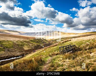 Ein Frühlingstag über Angram Moor in Yorkshire mit Little Whernside und einem Steg in der Ferne. Wogende Wolken bilden die Szene. Stockfoto