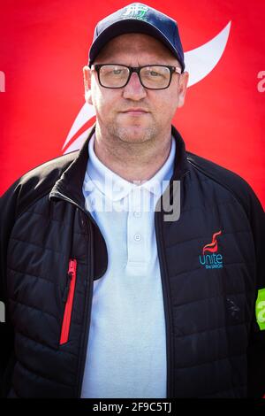 Manchester, Großbritannien. April 2021. Senior Steward, Colin Organisator der heutigen Veranstaltung, steht bei einem Protest in der Nähe eines Spruchbanners, der die Beendigung des Feuers und die Wiedererlanung fordert. Die Unite Union setzt ihre Demonstration vor dem Busbahnhof in Queens Road fort. Gewerkschaftsmitglieder sagten, dass das Busunternehmen Go North West von seinen Fahrern erwarte, dass sie mehr Stunden für das gleiche Geld arbeiten, und nannten es eine ‘Feuer- und Wiederanstellungstaktik'. (Foto von Andy Barton/SOPA Images/Sipa USA) Quelle: SIPA USA/Alamy Live News Stockfoto