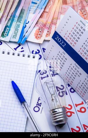 Zahlung von Stromrechnungen. Medizinische Maske und Kalender 2022. Kalender 2022 und Papierrubel. Stockfoto