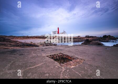 Leuchtturm an einem felsigen Strand an einem bewölkten Wintertag. Stockfoto