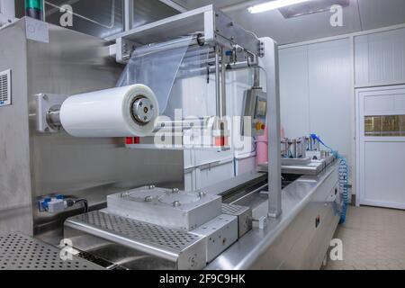 Verarbeitung von Verpackungen von Butter und Käse auf Vakuumverpackungsmaschine für Lebensmittel in der Lebensmittelindustrie. Verpackung von Lebensmitteln, Butter und Käse in PR Stockfoto