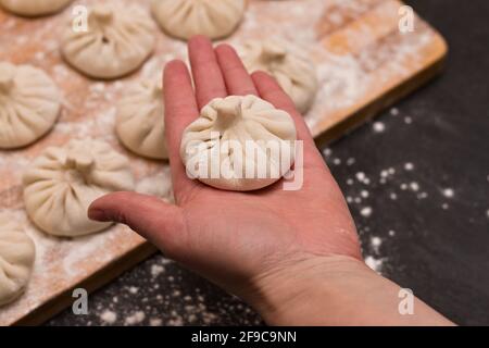 Frisch gekochte, rohe, traditionelle georgische Gerichte khinkali in der Palme des Küchenchefs. Stockfoto