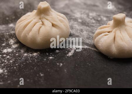 Georgische Khinkali mit Mehl auf einem schwarzen Tisch bestreut. Seitenansicht Stockfoto