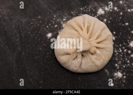 Rohe georgische Küche Gericht khinkali auf einem schwarzen Tisch. Draufsicht Stockfoto