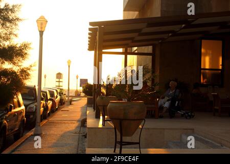 RHODOS, GRIECHENLAND - 01. Jul 2017: Horizontale Aufnahme von Menschen, die während des Sonnenuntergangs in Griechenland in einem Café essen. Schatten und Licht Stockfoto