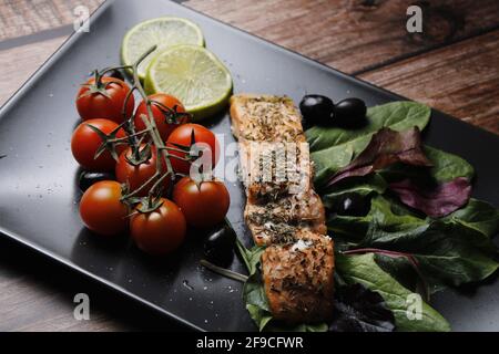 Teller Lachsfilet mit Spinat, Zitrone und Kirschtomaten Stockfoto