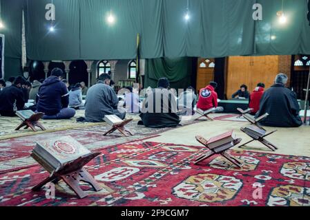 Srinagar, Indien. April 2021. Kaschmiri-Muslime rezitieren das islamische heilige Buch Koran während der Gemeinderezitation des Heiligen Koran am 4. Tag des Ramadan in an Imam Badah in Srinagar.der heiligste Monat des Islams im Ramadan ist eine Zeit des intensiven Gebets, des Fastens von Sonnenaufgang bis Sonnenuntergang und nächtlicher Feste. Khatam Al-Quran ist eine Zeremonie, die normalerweise gegen Ende des Ramadan von Muslimen abgehalten wird. Die Einhaltung markiert den Abschluss der Lektüre der 30 Kapitel (Juzuk) des Al-Quran. Kredit: SOPA Images Limited/Alamy Live Nachrichten Stockfoto