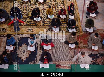 Srinagar, Indien. April 2021. Kaschmiri-Muslime mit Gesichtsmasken rezitieren das islamische heilige Buch Koran während der Gemeinderezitation des Heiligen Koran am 4. Tag des Ramadan in einem Imam Badah in Srinagar.der heiligste Monat des Islams im Ramadan ist eine Zeit des intensiven Gebets, des Fastens von Sonnenaufgang bis Sonnenuntergang und nächtlicher Feste. Khatam Al-Quran ist eine Zeremonie, die normalerweise gegen Ende des Ramadan von Muslimen abgehalten wird. Die Einhaltung markiert den Abschluss der Lektüre der 30 Kapitel (Juzuk) des Al-Quran. (Foto von Idrees Abbas/SOPA Images/Sipa USA) Quelle: SIPA USA/Alamy Live News Stockfoto