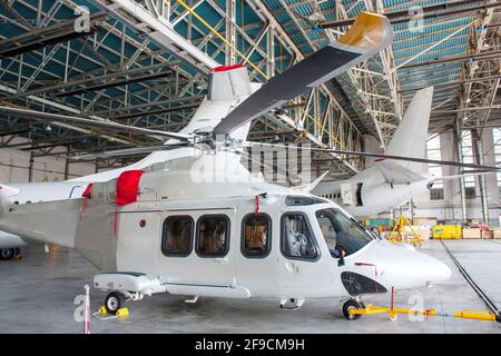 Passagierhubschrauber und Flugzeuge unter Wartung. Mechanische Systeme für Flugbetrieb prüfen. Rotorcraft und Flugzeuge im Hangar Stockfoto