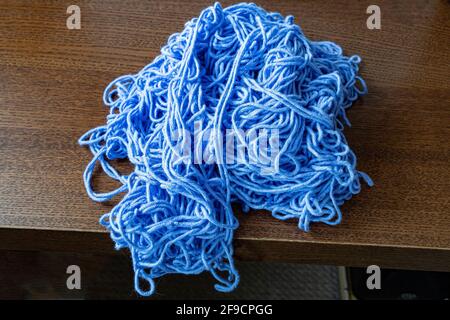 Auf einem großen Stapel verworrter dicker Strickfäden liegt ein Haufen Der Tisch Stockfoto