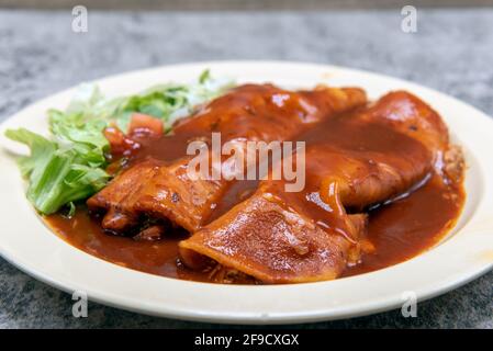 Hühnerenchiladas, die in schmackhafter roter Sauce auf einem Teller erstickt sind, sorgen für einen füllenden und herzhaften Vorspeise. Stockfoto