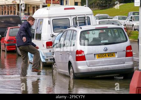 Flutung in Southend am Meer. Der Mensch wasiert durch Tiefseewasser zu seinem Auto. Die Frühjahrsflut brach gegen die Verteidigung des Meeres. Nasse Füße Stockfoto