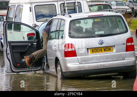 Flutung in Southend am Meer. Der Mensch wasiert durch Tiefseewasser zu seinem Auto. Die Frühjahrsflut brach gegen die Verteidigung des Meeres. Nasse Füße kommen ins Auto Stockfoto