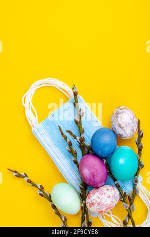 Helle Ostereier, medizinische Masken, Weidenzweige auf farbigem Hintergrund. Ostern Unter Quarantäne Stellen. Stoppen Sie COVID-19 VIRUS. Studio Photo Stockfoto