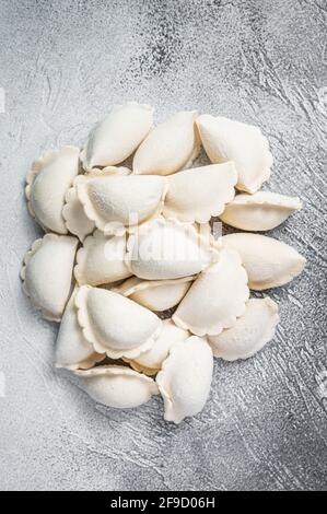 Rohe gefrorene Knödel pierogi auf einem Küchentisch. Weißer Hintergrund. Draufsicht Stockfoto