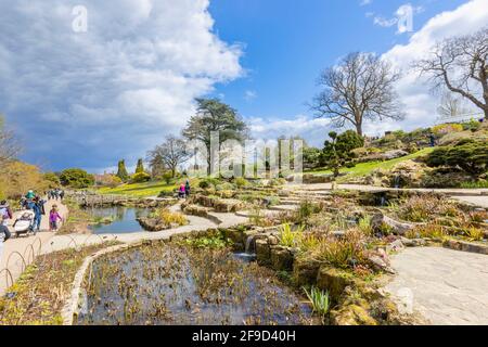 Blick über den Rock Garden im RHS Garden, Wisley, Surrey, Südostengland im Frühjahr mit aufziehenden grauen Wolken Stockfoto