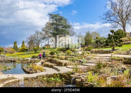 Blick über den Rock Garden im RHS Garden, Wisley, Surrey, Südostengland im Frühjahr mit aufziehenden grauen Wolken Stockfoto