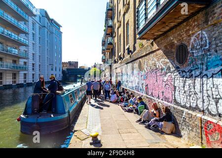 17. April 2021 - London, Großbritannien, Menschen sitzen an einem sonnigen Wochenende auf dem Treidelpfad entlang des Regent-Kanals in der Nähe des Camden Market, nachdem die Sperrung der Coronavirus-Pandemie gelockert wurde Stockfoto