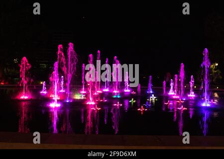 Heller, farbenfroher Brunnen vor einem dunklen Himmel Stockfoto