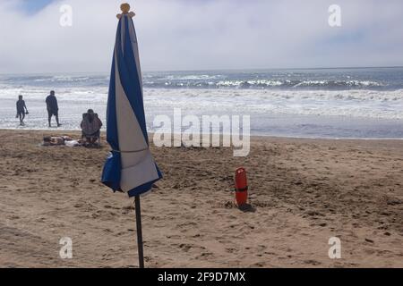 Sonnenschirm und Rettungsschwimmer am Strand an einem sonnigen Tag. Stockfoto