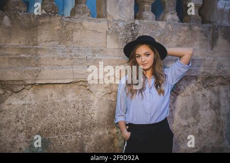 Schöne bosnisch kaukasische Frau in einem Hut posiert gegen die Wand Stockfoto
