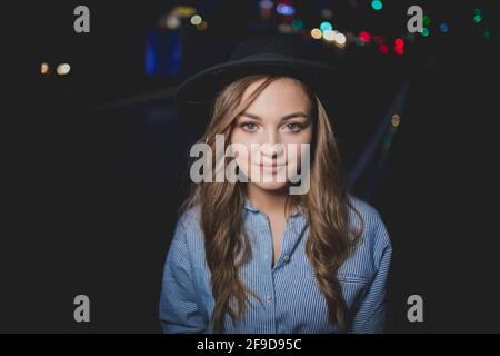 Schöne bosnisch kaukasische Frau in einem Hut posiert in der Nachts auf der Straße Stockfoto