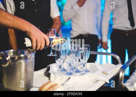 Selektiver Fokus auf die Hand eines Kellners, der Champagner auf Clear gießt Brille Stockfoto