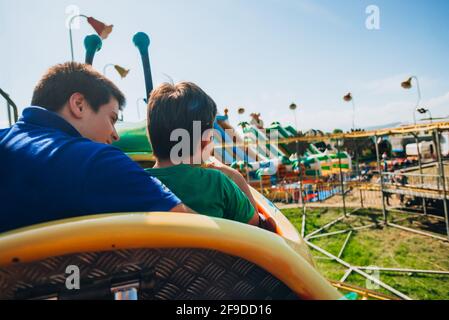 Fröhliche junge Menschen reiten in Achterbahn Zug an Vergnügungspark Stockfoto